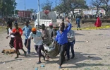 Des gens transportent le corps d'une victime de l'attentat-suicide au camion piégé qui a fait plus de 20 morts près de l'entrée du port de Mogadiscio