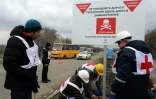 Des agents de la Croix-rouge installent des panneaux de prévention contre les mines "Danger de mines! Ne quittez pas la route!", sur le bord d'une route près du village de Berezové, dans la région de Donetsk, le 28 mars 2016