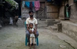 Mizan Hossain, blessé sur un chantier de démantèlement de bateaux, et son fils devant leur maison, le 19 février 2025 à Chittagong, au Bangladesh