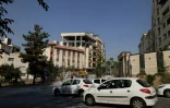 Des automobilistes passent devant un bâtiment endommagé après qu’il a été visé par une frappe israélienne dans la capitale iranienne, Téhéran, le 13 juin 2025