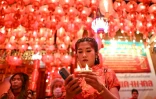 Une jeune femme en robe rouge de style chinois prie au temple Wat Mangkon Kamalawat dans le quartier chinois de Bangkok, à la veille de la nouvelle année lunaire du serpent, le 28 janvier 2025 en Thaïlande