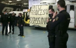 Des gendarmes se tiennent à côté de leurs camions sur lesquels a été déployée une banderole "L'Etat français assassin", le 4 mars 2022 à Ajaccio