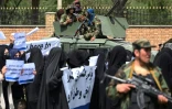 Des combattants talibans encadrent une marche d'Afghanes en niqabs noirs lors d'un rassemblement devant l'Université Shaheed Rabbani, le 11 septembre 2021 à Kaboul