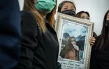 Une proche tient un portrait d'une des victimes de l'incendie dans un bar, le 14 juillet 2026 à l'hôpital général de la police de Bangkok  en Thaïlande