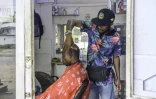 Junior Kilembe, propriétaire d'un salon de coiffure en bois, coupe les cheveux d'un client à Kinshasa, le 17 octobre 2024 en RDC