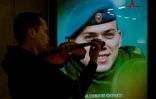 Un musicien de rue devant uen affiche encouregeant à s'engager dans l'armée, dans le métro de Moscou le 2 juin 2023