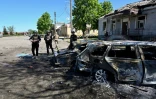 Des policiers ukrainiens près d'une voiture détruite par une frappe russe à Zlotchiv, dans la région de Kharkiv, le 1er mai 2024