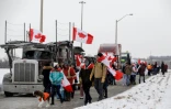 Des sympathisants accompagnent un convoi de camionneurs à destination d'Ottawa pour manifester contre l'obligation vaccinale et les restrictions sanitaires, le 23 janvier 2022 à Toronto, au Canada