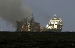 Un bateau de la société néerlandaise Smit remorque le porte-conteneurs MV X-Press Pearl (g), ravagé par un incendie depuis douze jours, pour l'éloigner des côtes de Colombo, le 2 juin 2021 au Sri Lanka