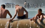 Des personnes se rafraîchissent dans le bassin de la fontaine du Trocadéro, le 2 août 2018 à Paris, pendant un épisode de canicule