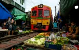 Un train de passagers traverse le marché de Maeklong, dans la province de Samut Songkhram, le 4 juin 2022 en Thaïlande