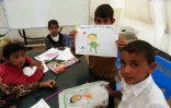 Des enfants irakiens qui ont fui les combats à Mossoul montrent les dessins qu'ils ont faits au camp de Hasan Sham situé à 30 km à l'est de Mossoul, le 31 mars 2017