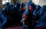 Des femmes en burqa et leurs enfants attendent dans un poste de santé du village d'Aab Bareek du district d'Argo, dans la province de Badakhshan, le 26 février 2024 en Afghanistan