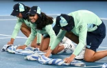 Des ramasseurs de balle de l'Open d'Australie épongent un court mouillé par la pluie, le 20 janvier 2020 à Melbourne