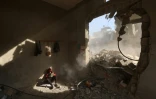 Un garçon palestinien lit un livre dans les décombres d'une maison après des frappes israéliennes dans le camp de réfugiés de Nousseirat, dans le centre de la bande de Gaza, le 29 avril 2025
