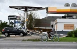 Un cycliste roule devant une station d'essence endomagée, à Kenner, en Louisiane, le 30 août 2021