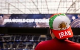 Un spectateur porte une casquette avec le drapeau utilisé par l'Iran avant la révolution islamique, et un drapeau israélien, à l'intérieur du SoFi Stadium à Inglewood, près de Los Angeles, le 15 juin 2026