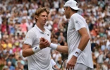 Le Sud-Africain Kevin Anderson (g), qualifié pour la finale de Wimbledon, serre la main de son adversaire, l'Américain John Isner, à la fin d'une rencontre marathon, le 13 juillet 2018