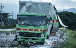 Un camion endommagé est laissé sur une route jonchée de débris à la suite d'une explosion survenue au centre commercial Aeon Mall à Kumamoto, à Kashima, dans le sud du Japon, le 29 juillet 2026, après qu'un tremblement de terre a frappé la région