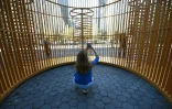 Une visiteuse dans la "Cage dorée" de l'artiste chinois Ai Weiwei devant son installation  à proximité de la Trump Tower à New York, le 10 octobre 2017