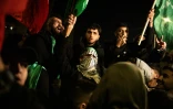 Des Palestiniens brandissant des drapeaux du Hamas attendent avec des membres de leur famille et des amis la libération de prisonniers détenus par Israël, à Baytunya, à l'extérieur de la ville de Ramallah en Cisjordanie, le 19 janvier 2025