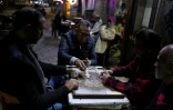 jouent aux dominos à la terrasse d'un café avant la fermeture en application du couvre-feu, dans le centre-ville du Caire, le 2 avril 2026 en Egypte
