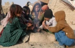 Des enfants déplacés se réchauffent autour d'un feu dans la province de Hérat, le 6 décembre 2022 en Afghanistan