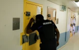 Un agent pénitentiaire regarde par le judas d'une porte à l'intérieur d'une cellule de l'Unité pour détenus violents de la prison de Fleury-Mérogis, le 21 juin 2023 dans l'Essonne