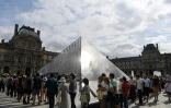 Des touristes font la queue devant l'entrée de la pyramide du Louvre à Paris le 19 juillet 2019