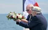 Des vétérans britanniques se préparent à jeter une gerbe de fleurs dans la mer depuis le pont d'un ferry lors d'une cérémonie au large de Portsmouth, le 4 juin 2024, dans le cadre des commémorations du « jour J »