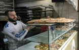 Un commerçant met en vitrine un plateau de pâtisserie à Alep le 11 décembre 2024.