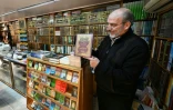 Un libraire montre un ouvrage qui aurait été interdit sous le régime déchu de Bachar al-Assad, dans une librairie de Damas, le 26 janvier 2025