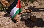 Un drapeau palestinien sur les lieux d'une attaque de colons israéliens qui a coûté la vie à plusieurs Palestiniens dans le village de Abou Falah, au nord-est de Ramallah, le 12 mars 2026