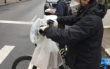 Un livreur porte masque, gants et sacs en plastique pour se protéger les mains sur son vélo, le 17 mars 2020 à New York

