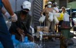 Des habitants de Caracas remplissent leurs bidons d'eau à une bouche à incendie le 27 mars 2020