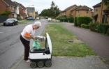 Sheila, 71 ans, récupère ses courses transportées jusque chez elle par un robot autonome, appelé Starship, à Milton Keynes, en Angleterre, le 20 septembre 2021