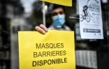 Un pharmacien accroche un affichette sur sa vitrine indiquant que des masques sont en vente, Ă Paris le 29 avril 2020