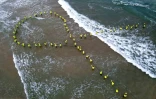 Des proches d'otages israéliens détenus à Gaza forment un ruban jaune sur une plage de Tel-Aviv pour réclamer leur retour, le 28 mai 2025