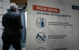 Un votant passe devant une affiche dans un bureau de vote pour le premier tour des élections municipales, le 15 mars 2020 à Paris