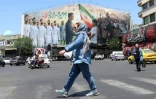 Une Iranienne passe devant un panneau montrant l'équipe de football de l'Iran, à Téhéran, le 18 mai 2026