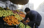 L'épicier Imadeddine al-Souda arrange son étal de fruits et légumes dans une rue d'Alep, le 21 janvier 2017 en Syrie