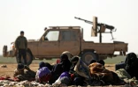 Des civils ayant fui les combats contre le groupe Etat islamique (EI) dans son ultime réduit de Syrie, et derrière eux un combattant des Forces démocratiques syriennes (SDF), près du village de Baghouz, le 3 février 2019