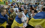 Des prisonniers de guerre ukrainiens libérés enveloppés dans le drapeau national passent devant une foule tenant des portraits de leurs proches et amis disparus ou capturés, à leur arrivée après un échange de prisonniers dans la région de Tcherniguiv, le 26 juin 2025, en Ukraine