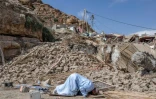 Photo prise le 12 septembre 2023 dans le village de Imi n'Talat, dans le centre du Maroc, montrant un homme priant devant des décombres de bâtiments après un puissant séisme