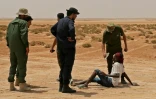 Des gardes-frontières libyens donnent à boire à des migrants africains à leur arrivée à la frontière entre la Libye et la Tunisie, près d'Al'Assah, le 30 juillet 2023