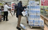 Un homme achète du papier toilette dans un magasin à Londres, le 14 mars 2020