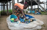 Une femme trie des objets en plastique ramassés dans le fleuve Congo sur l'ßle de Kimpoko, à Kinshasa, le 27 avril 2026 en RDC