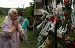 Une femme rend hommage à des personnes qui déposent des fleurs devant l'entrée de la propriété de l'acteur français Alain Delon, à Douchy, dans le centre de la France, le 18 août 2024