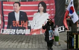 Une partisane se tient devant une banderole représentant l'ancien président sud-coréen destitué Yoon Suk Yeol et son épouse Kim Keon Hee, près du tribunal central de Séoul, le 16 janvier 2026