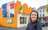 Laurita Blewitt, cousine éloignée de Joe Biden, pose devant le portrait du candidat à la présidentielle américaine, le 7 octobre 2020 à Ballina en Irlande